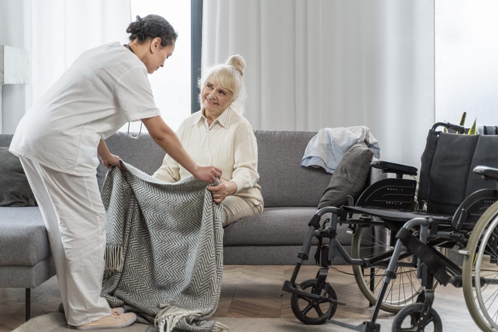 Caregiver assisting a senior woman in a comfortable living space as part of our assisted living resources for families exploring assisted living Charlotte NC.